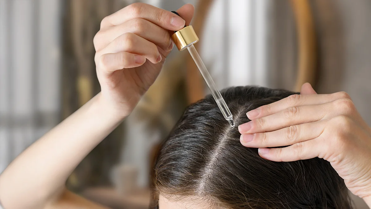 A woman applying FAQ best hair serum on her scalp